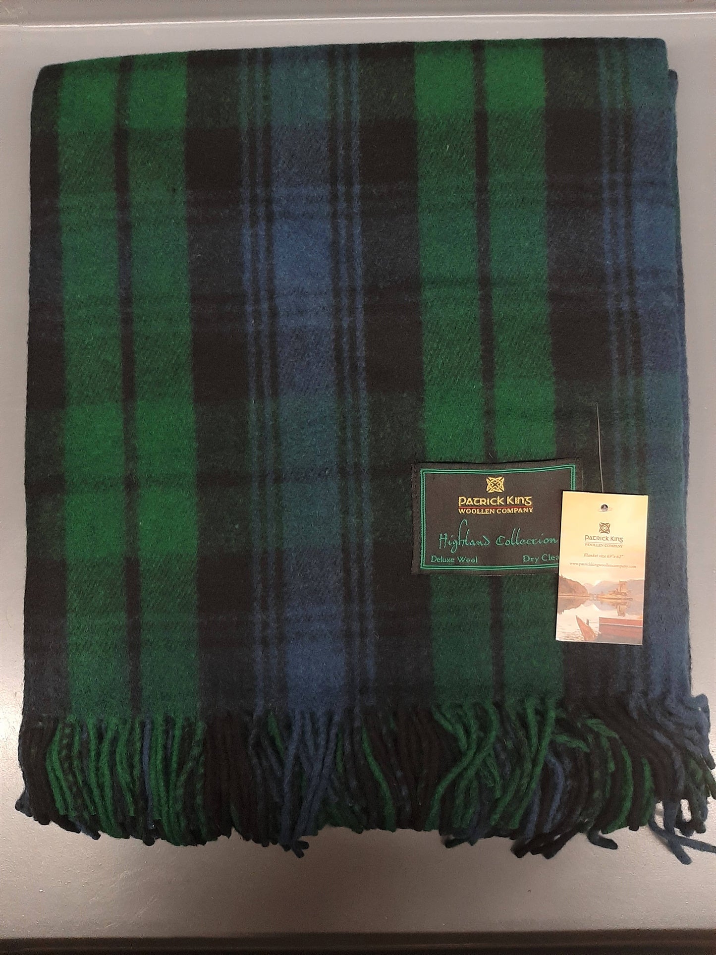 Green and black plaid blanket with a tag on a white background